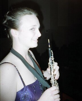Me with an updo in a sparkly dress holding my oboe with an attached neck strap.
